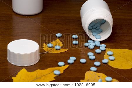 Blue pills and medicine bottle on wooden background