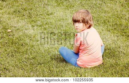 Offended Young Girl Sitting On The Grass