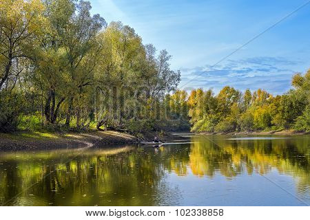Autumn landscape with fisherman in a boat on the river