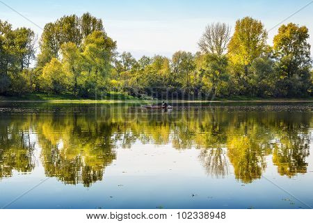 Rustic fisherman sails on the boat on the autumn river