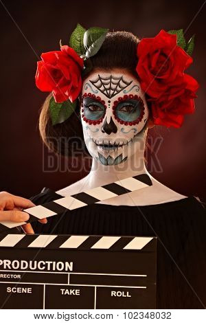 Filming woman in halloween santa muerte mask. Clapper board.