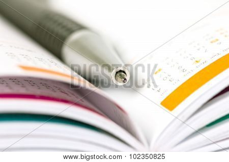 Selective Focus Of Ball Pen On Opened Lined Diary Book With Calendar Page