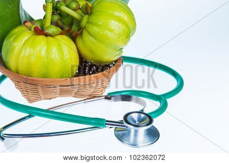 Close Up Garcinia Cambogia And Stethoscope On White Background.