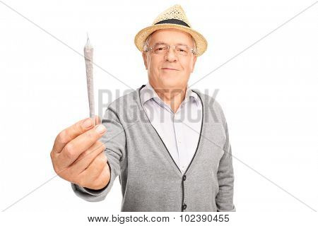 Cheerful mature man handing medicinal marijuana towards the camera isolated on white background
