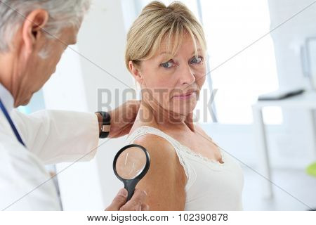 Elderly woman consulting doctor for skin control
