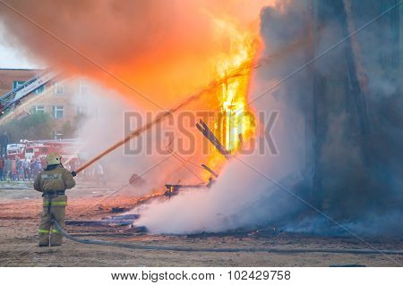 NOVYY URENGOY, RUSSIA - AUGUST 3, 2015: Fireman extinguishes a burning old wooden residential house
** Note: Visible grain at 100%, best at smaller sizes