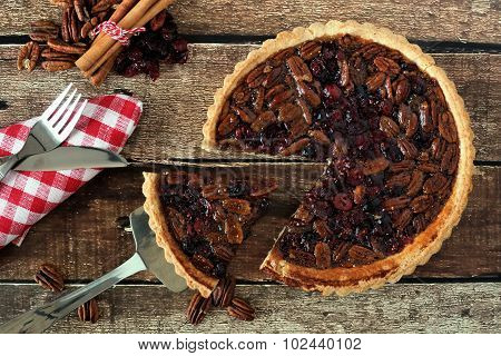 Pecan and cranberry pie, rustic table scene with slice removed