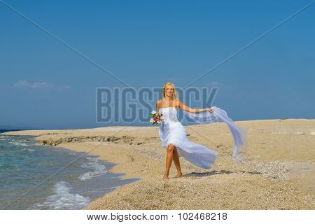 Young bride in wedding drees having fun on the beach in Greece