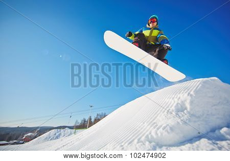 Active young man on snowboard hanging over snowdrift