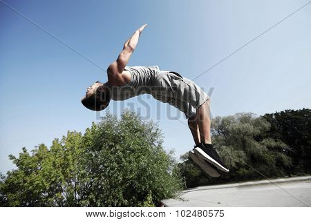 fitness, sport, parkour and people concept - young man jumping in summer park