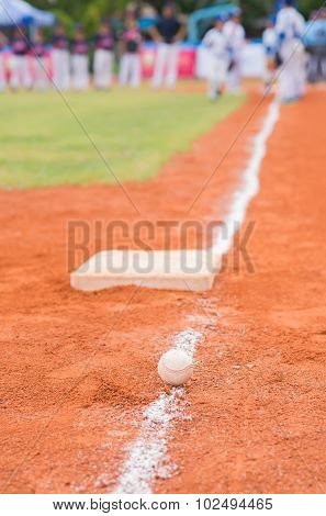 Baseball And Base On Baseball Field With Players Practising On Background
