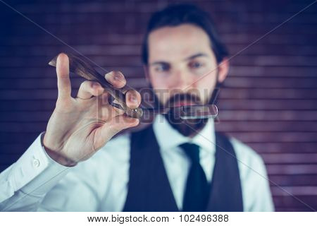 Hipster hlding razor against brick wall