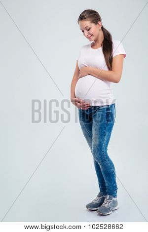 Full length portrait of a pregnant woman caressing her belly isolated on a white background