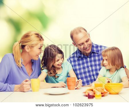 food, family, children, hapiness and people concept - happy family with two kids having breakfast at home
