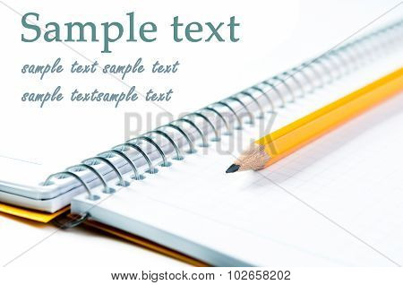 Composition of yellow pencil lying on blank notebook