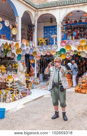 SAFI, MOROCCO, APRIL 6, 2015: Senior tourist takes photos in the pottery souk in Safi, capital of ceramics craft