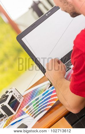 Man working on laptop with palette, colormap spread out next to it