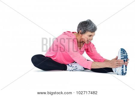 Mature woman touching toes while exercising over white background