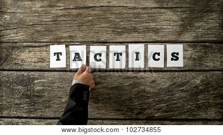 Overhead View Of Strategic Business Partner Assembling The Word Tactics