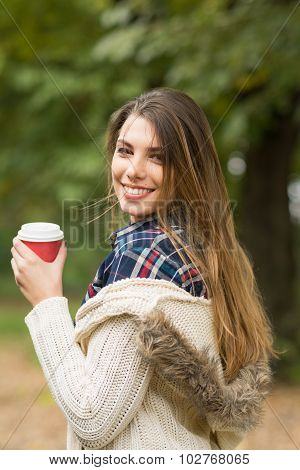 Happy young woman with takeaway coffee in autumn