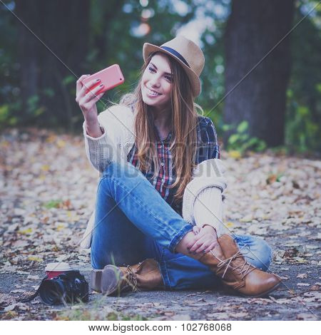 Fashionable young woman taking a selfie outdoors in autumn