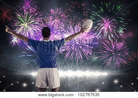 Rugby player about to throw a rugby ball against fireworks exploding over football stadium