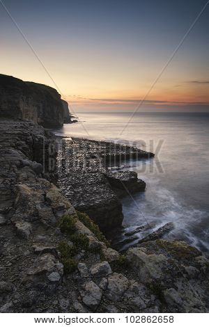 Stunning Coastal Landscape With Long Exposure Waves Crashing At Sunrise