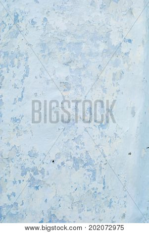 An old whitened white with a blue wall with cracks for a background or texture of pale color vertical.
