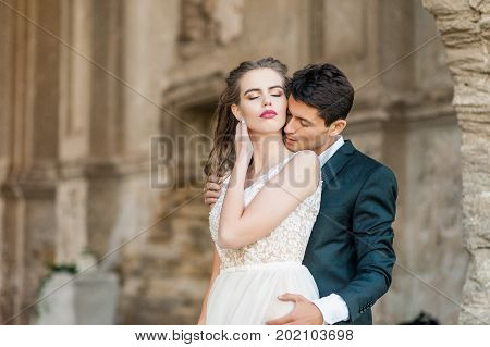 Beautiful wedding couple bride and groom at wedding day indoors at old church. Happy marriage couple indoors soft sunny lights. Loving man and woman at marriage day.