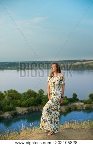Half length portrait of charming positive woman dressed in long white summer dress happy smiling in sunset background. Beautiful woman enjoy.
