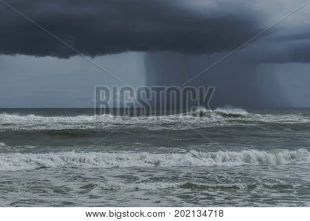 Dark dramatic tropical storm coming ashore at Pensacola Florida beach. Water spout descending from dark cloud.