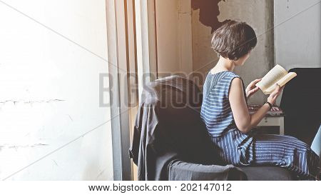 Cute teenage girl in asia reading book on black sofa in living room