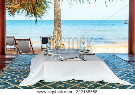 Cafe Table on a tropical sandy beach with sea on background, Rabbit island, Cambodia.  Table Set up for a romantic meal on the beach
