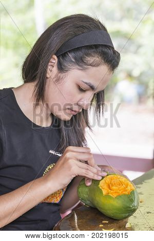 Asian Thai woman carving papaya fruit as rose flower