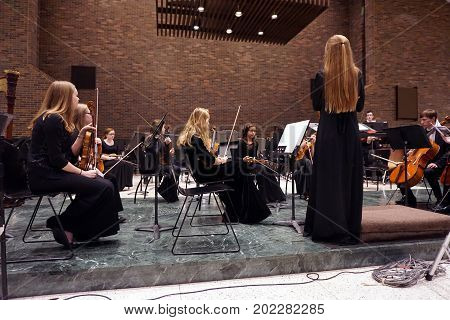 ROMEOVILLE, ILLINOIS / UNITED STATES - OCTOBER 26, 2016: The concert mistress of the Metropolitan Youth Symphony Orchestra (MYSO) stands before the orchestra members, to direct the tuning of instruments, prior to a concert at Lewis University.