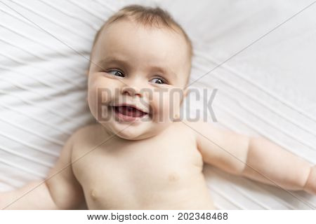 A Cute happy 7 month baby girl in diaper lying and playing