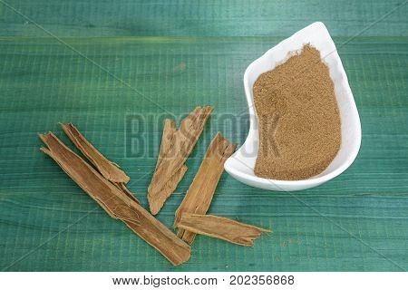 Cinnamon powder, spices on green wooden background