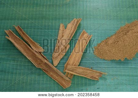 Cinnamon powder, spices on green wooden background