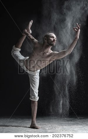 Flexible yoga man practices yoga or pilates, performing Natarajasana, Lord of the Dance pose