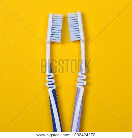 twi Toothbrushes on the yellow background. Top view