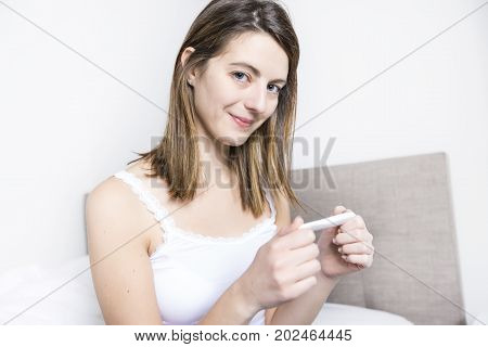 A Young woman in bedroom at home wearing in white check pregnant test