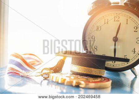 Graduation cap on Golden medals with clock graduate education in university Competitions and Educational study concepts. Success in study famous institution Concept of winner abroad international.