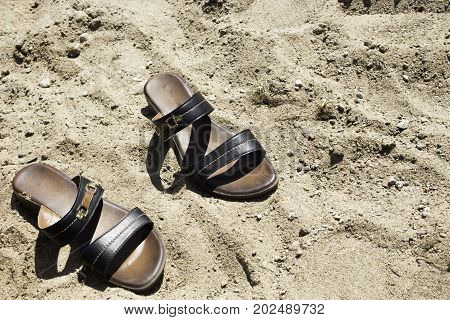 brown women's sandals lying on the sand