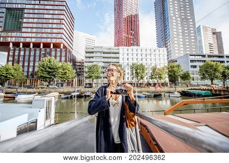 Young woman traveling at the modern harbor with skyscrapers on the background in Rotterdam city