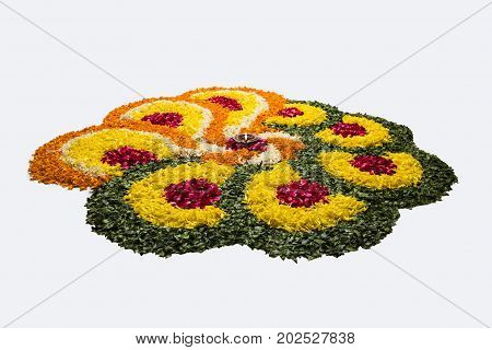 flower rangoli for Diwali or pongal or onam made using marigold or zendu flowers and red rose petals over white background with diwali diya in the middle, selective focus