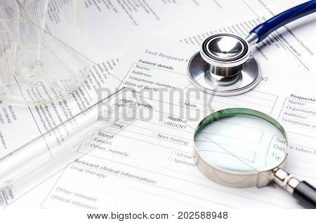 stethoscope magnifying glass test tube beaker and patient information form on desk healthcare technology medical report record and history patient concept selective focus