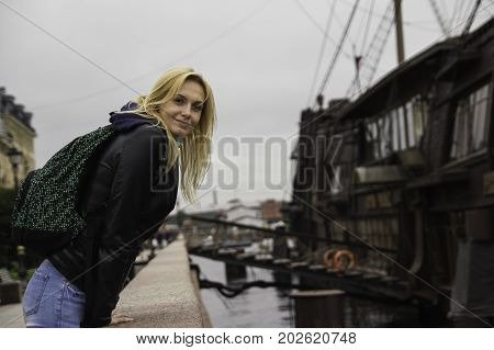 Beautiful Girl In A Jacket Looks At The Camera Leaning On A Handrail In St. Petersburg