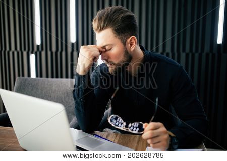 Exhausted Tired Businessman Working On Laptop At Office, Massaging Nose Bridge, Holding Glasses, Fee