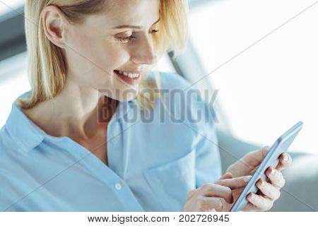 Staying tuned in. The close up of a charming young woman reading newsfeed using her smartphone, staying tuned in to the current situation in the world