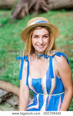 Beautiful girl wearing blue dress collect flowers in basket in the green grass wood